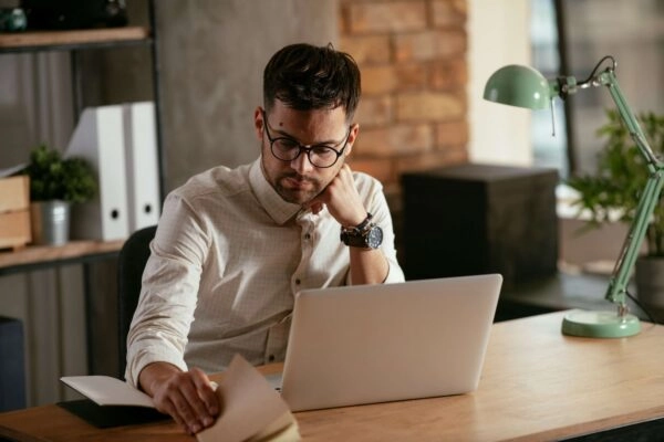 Man flicking through notebook at desk