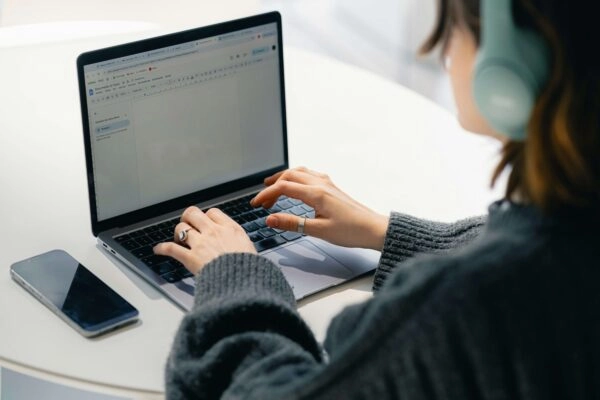 Woman on laptop with phone in view